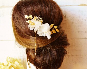 Pic à chignon fleurs fraîches éternelles blanc ivoire sur feuilles dorées avec pendants ornés de perles nacrées.