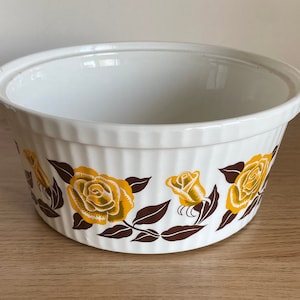May include: White ceramic baking dish with a brown and yellow floral design. The dish has a fluted rim and is ideal for baking casseroles, desserts, or other dishes.