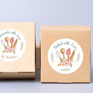 Puede incluir: Dos cajas de cart&oacute;n marr&oacute;n con pegatinas redondas blancas. Las pegatinas tienen una ilustraci&oacute;n de acuarela de utensilios de cocina, flores y vegetaci&oacute;n. El texto en las pegatinas dice "Homemade with Love by Christina" y "Baked with Love".