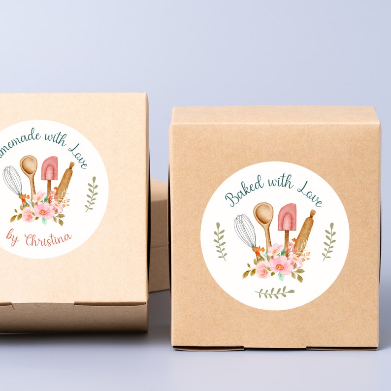 Puede incluir: Dos cajas de cart&oacute;n marr&oacute;n con pegatinas redondas blancas. Las pegatinas tienen una ilustraci&oacute;n de acuarela de utensilios de cocina, flores y vegetaci&oacute;n. El texto en las pegatinas dice "Homemade with Love by Christina" y "Baked with Love".