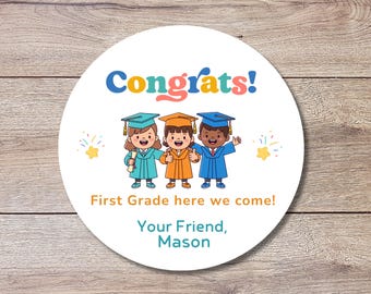 May include: A round sticker with the word "Congrats!" in blue, orange, and pink. Below are three cartoon graduates in teal, orange, and blue graduation gowns. The text "First Grade here we come!" and "Your Friend, Mason" are also included.
