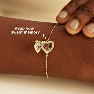 May include: A gold-toned heart-shaped locket bracelet with a delicate chain. The locket is open, revealing a small pressed flower inside. The text "Keep your sweet memory" is printed near the locket with a small arrow pointing to it.
