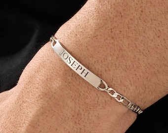Pode incluir: Um bracelete de corrente de prata com uma placa retangular gravada com o nome "JOSEPH".