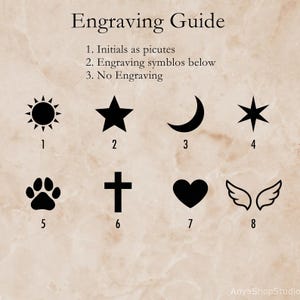 May include: An engraving guide with the text Engraving Guide, 1. Initials as picutes, 2. Engraving symblos below, 3. No Engraving. Below are eight black icons numbered 1 through 8: a sun, star, crescent moon, six-pointed star, paw print, cross, heart, and wings.