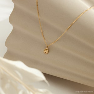 May include: A delicate gold chain necklace with a small, dainty flower pendant.