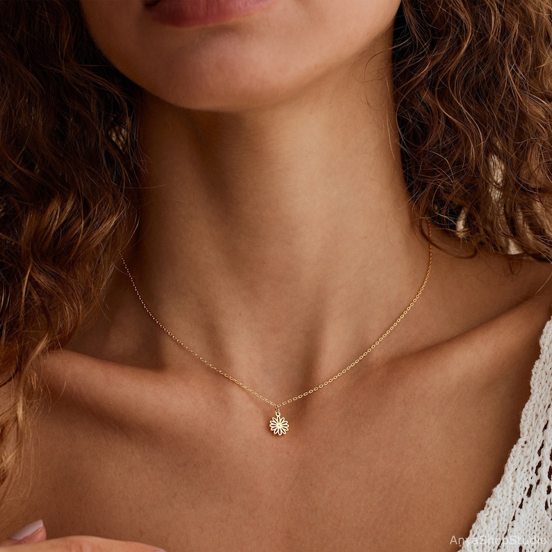 May include: A delicate gold chain necklace with a small, dainty flower pendant.