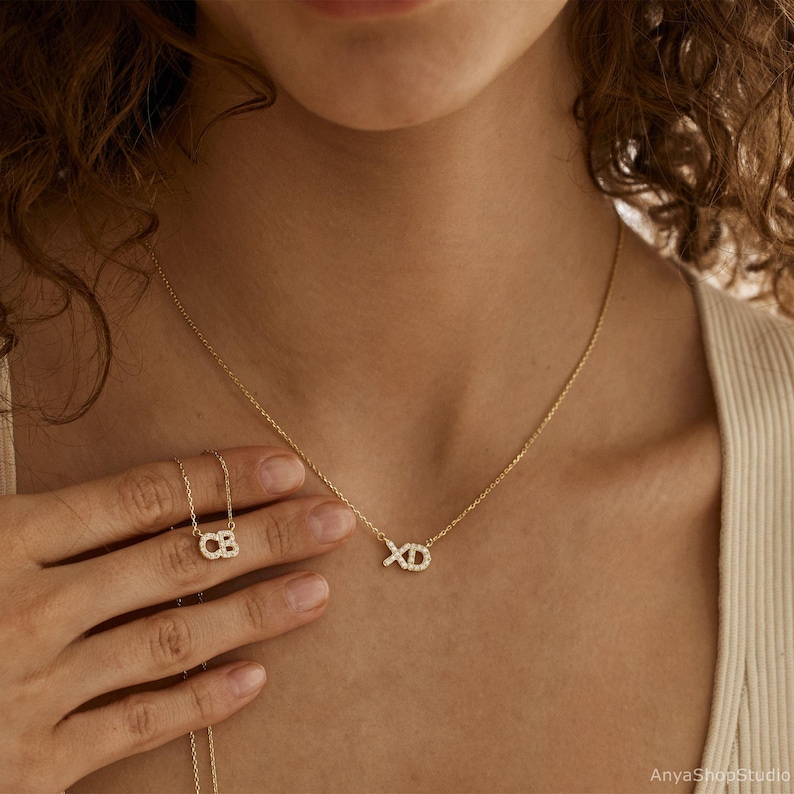 May include: A gold necklace with a delicate chain and a pendant that says "XO" in small, sparkling diamonds.