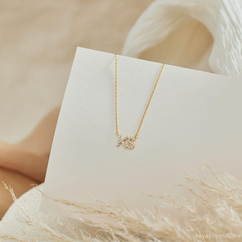May include: A gold necklace with a small pendant in the shape of the letters "XO" set with tiny clear stones.