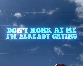 May include: A blue car window sticker with the text "DON'T HONK AT ME I'M ALREADY CRYING" in a retro font.