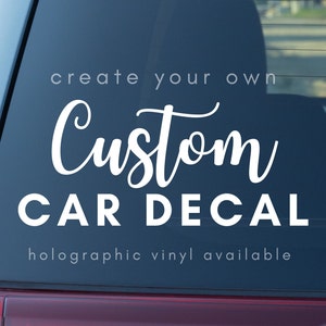May include: A white custom car decal on a blue car window. The decal says "create your own Custom CAR DECAL" and "holographic vinyl available".