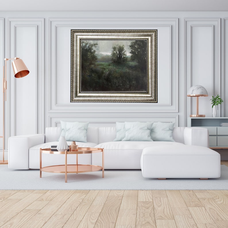 Puede incluir: Un sof&aacute; seccional blanco con almohadas de color azul claro se encuentra frente a una pintura de paisaje enmarcada. Una mesa de caf&eacute; de cobre con dos niveles se encuentra frente al sof&aacute;.