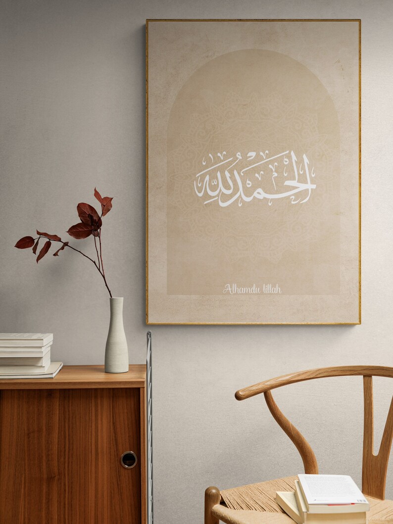 Puede incluir: Una impresi&oacute;n en lienzo beige con un dise&ntilde;o de caligraf&iacute;a &aacute;rabe blanca en forma de arco. El texto dice "Alhamdu Lillah", que se traduce como "Alabado sea Dios".