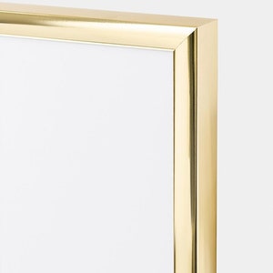 May include: A gold picture frame with a smooth, polished finish. The frame is made of metal and has a simple, modern design.