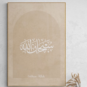 Puede incluir: Una impresi&oacute;n en lienzo beige con marco dorado presenta caligraf&iacute;a &aacute;rabe en blanco, que dice "Subhan Allah" en un arco decorativo. El fondo es un beige sutil con un patr&oacute;n texturizado.