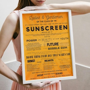 May include: A framed poster with a white border and an orange background. The poster features black text with the words "SUNSCREEN" and other phrases. The poster is held by a person wearing a pink dress.