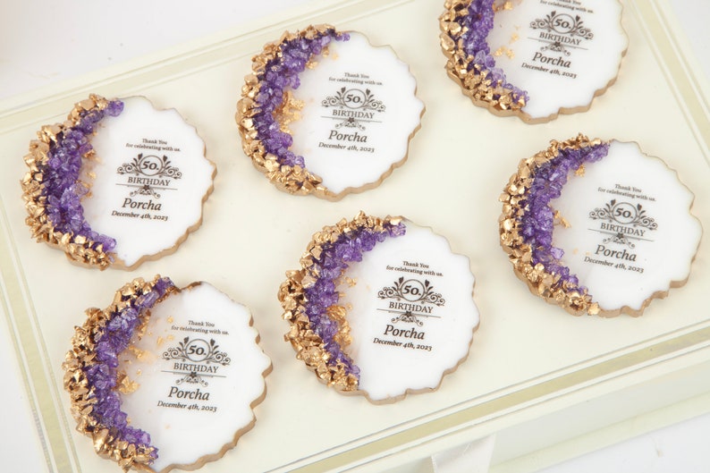 Puede incluir: Seis galletas redondas blancas decoradas con glaseado morado y dorado. Cada galleta tiene un dise&ntilde;o dorado con el texto "50 cumplea&ntilde;os Porcha 4 de diciembre de 2023".