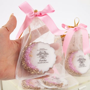 Puede incluir: Bolsas de regalo rosas y blancas con un adorno redondo de pastel blanco con purpurina dorada y un dise&ntilde;o rosa y blanco. El adorno de pastel tiene el texto "Thank you for celebrating with us on our 50th Birthday Porcha December 6th, 2023".