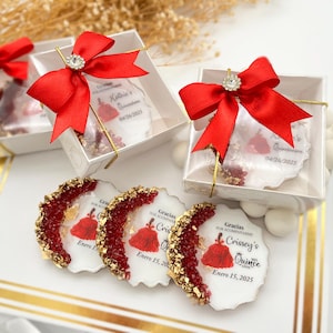 Op de afbeelding: Drie ronde witte onderzetters met rode en gouden glitteraccenten. Elke onderzetter heeft een gedrukte afbeelding van een vrouw in een rode jurk met de tekst "Gracias por acompa&ntilde;arme Crissey's Quince A&ntilde;os Enero 15, 2025".