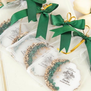 Puede incluir: Bolsas de regalo verdes y doradas con cintas de sat&eacute;n blancas y una etiqueta blanca con el texto "Gracias por celebrar con nosotros. Feliz cumplea&ntilde;os Parcha 4 de diciembre de 2023".