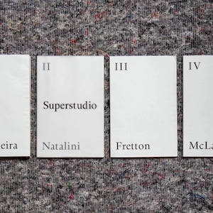 May include: Four white cards with Roman numerals I to IV and the names Siza Vieira, Superstudio Natalini, Fretton, and McLaughlin printed on them.