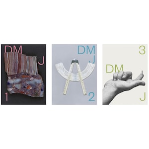 May include: A triptych featuring three distinct panels. The first shows a layered, multi-colored rock fragment with the text DM J 1. The second displays a white folding ruler forming an arc with the text DM J 2. The third shows a hand with a small ring on a finger and the text DM 3 J.