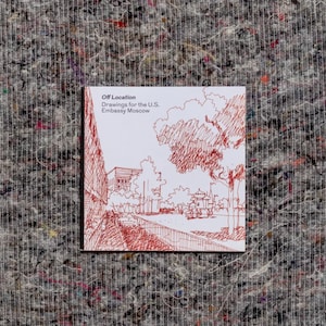 Puede incluir: Una cubierta de libro blanca con dibujos en tinta roja de una escena de calle con árboles y edificios. El título del libro es "Off Location: Drawings for the U.S. Embassy Moscow."