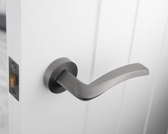 Paquete de puerta Sines, con un par de manijas, pestillo, bisagras y tornillos de fijación. La palanca tiene un giro angular para un agarre óptimo.