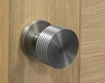 Para ryflowanych, podszytych, wstążkowych klamek do drzwi wpuszczanych, bez sprężyny, odpowiednich jako gałki przejściowe lub atrapy, dostępne w opcji zapewniającej prywatność. Nowoczesne