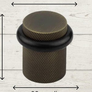 May include: Antique brass doorstop with a black rubber stopper. The doorstop is 40mm tall, 38mm in diameter, and 30mm wide.