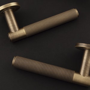 El par de manijas de puerta con palanca moleteada Spitfire en roseta redonda fabricadas en latón macizo, de paso, ficticias, de privacidad o con cerradura, todas disponibles