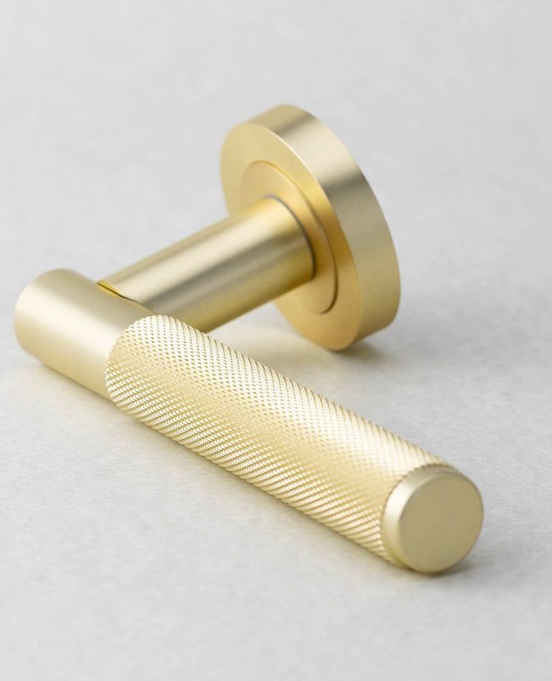 May include: A gold-colored door handle with a textured grip. The handle has a cylindrical shape with a round base and a circular backplate. The metal hardware is designed for interior doors.