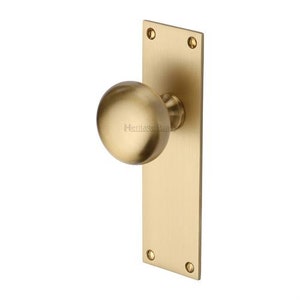 Peut inclure: Un bouton de porte en laiton avec une poign&eacute;e ronde et une plaque arri&egrave;re rectangulaire. Le bouton de porte est de couleur or chaud et pr&eacute;sente un design classique. La plaque arri&egrave;re comporte quatre trous de vis.