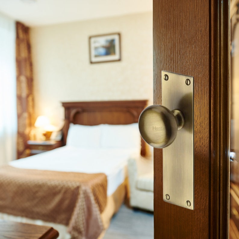 Peut inclure: Une porte en bois partiellement ouverte, orn&eacute;e d'un bouton de porte en laiton avec le mot "Henley" grav&eacute;. L'arri&egrave;re-plan r&eacute;v&egrave;le une chambre avec un lit, une table de chevet et un tableau encadr&eacute;.
