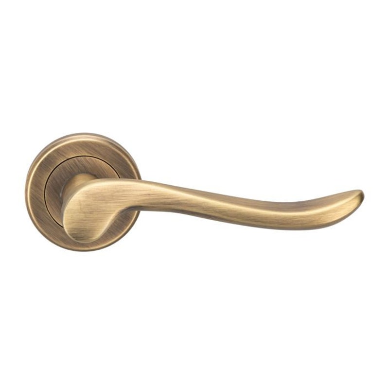 May include: A brushed antique brass door handle with a curved lever and a round base.