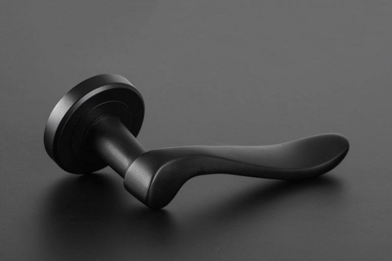 May include: A black door handle with a curved lever. The handle is made of metal and has a smooth finish.