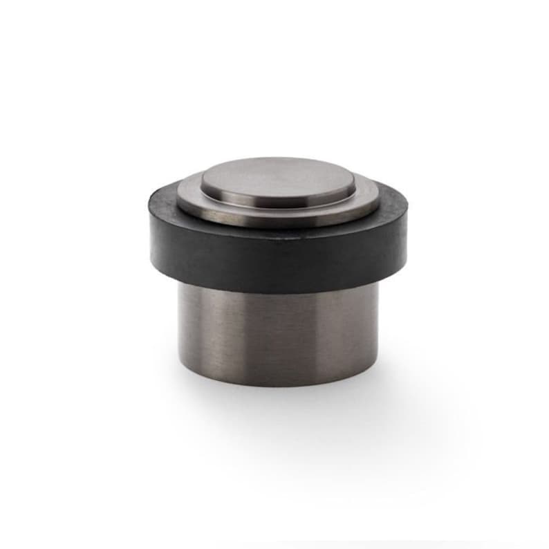 May include: A silver doorstop with a black rubber base. The doorstop has a round top and a cylindrical base.