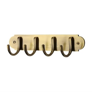 May include: Antique brass wall mounted hook rack with four hooks. The rack has a rectangular shape with rounded edges and a slightly raised centre section.