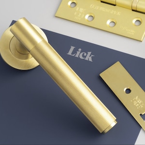 May include: A gold door handle with a ribbed design. The handle is on a blue background with the word "Lick" printed in white.