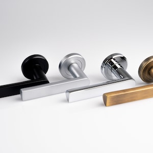 May include: Three door handles in different finishes: black, silver, and brass. The handles are all the same style, with a square lever and a round base.