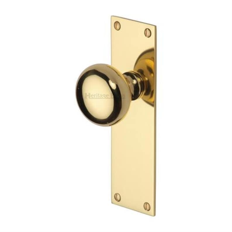 Peut inclure: Un bouton de porte en laiton poli avec une poign&eacute;e ronde et une plaque arri&egrave;re rectangulaire. Le bouton de porte porte le mot "Heritage" imprim&eacute; sur la poign&eacute;e. La plaque arri&egrave;re comporte quatre trous de vis.