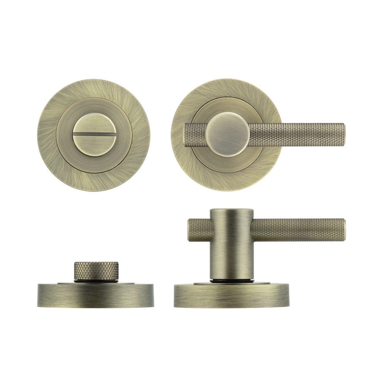 May include: Antique brass door hardware set. The set includes a round door knob with a textured handle, a round plate with a slotted screw, and a smaller round piece with a textured top. The hardware has a vintage aesthetic.