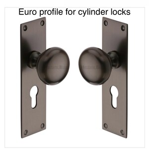 Peut inclure: Deux ensembles de poign&eacute;es de porte gris fonc&eacute; avec des trous de serrure et des boutons ronds. Le texte "Euro profile for cylinder locks" est en haut. Chaque ensemble a une plaque arri&egrave;re rectangulaire avec quatre trous de vis.