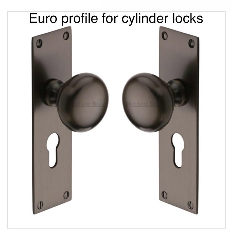 Peut inclure: Deux ensembles de poign&eacute;es de porte gris fonc&eacute; avec des trous de serrure et des boutons ronds. Le texte "Euro profile for cylinder locks" est en haut. Chaque ensemble a une plaque arri&egrave;re rectangulaire avec quatre trous de vis.