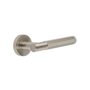 May include: A brushed nickel door handle with a textured grip. The handle features a round backplate and a cylindrical lever with a cross-hatched pattern for enhanced grip. The design is modern and minimalist.