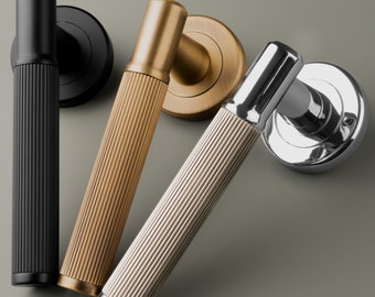 May include: Three door handles with different finishes: black, brass, and chrome. Each handle has a fluted design and a round base.
