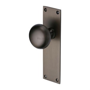Peut inclure: Une poign&eacute;e de porte en bronze fonc&eacute; avec une poign&eacute;e ronde et une plaque arri&egrave;re rectangulaire. La quincaillerie est fix&eacute;e avec quatre vis et pr&eacute;sente un design classique et minimaliste. La poign&eacute;e de porte est probablement en m&eacute;tal.