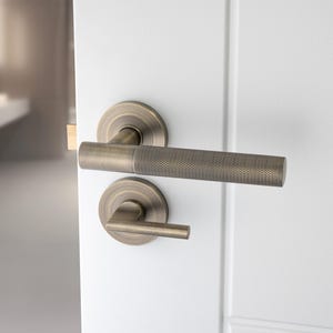 May include: A brushed nickel door handle with a lever design. The handle has a textured finish and a square shape.