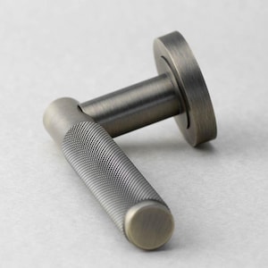 May include: A close-up of a bronze-toned door handle. The handle features a textured grip with a circular end cap. The base of the handle is a circular plate. The hardware is made of metal and has a vintage aesthetic.
