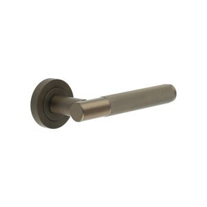 May include: A bronze-toned door handle with a textured grip. The handle features a circular base, a cylindrical neck, and a textured, cylindrical grip. The design is modern and minimalist, suitable for interior doors.