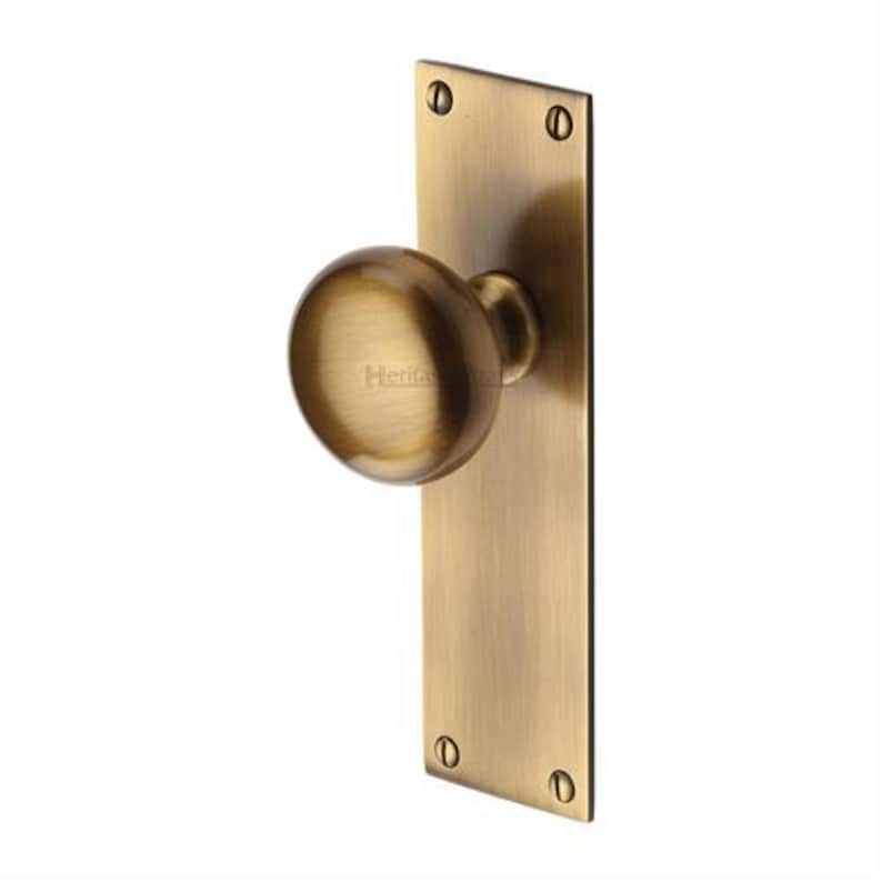 Peut inclure: Un bouton de porte en laiton avec une poign&eacute;e ronde et une plaque arri&egrave;re rectangulaire. La quincaillerie a une finition bross&eacute;e et est fix&eacute;e avec quatre vis. La poign&eacute;e de porte est con&ccedil;ue pour les portes int&eacute;rieures ou ext&eacute;rieures.
